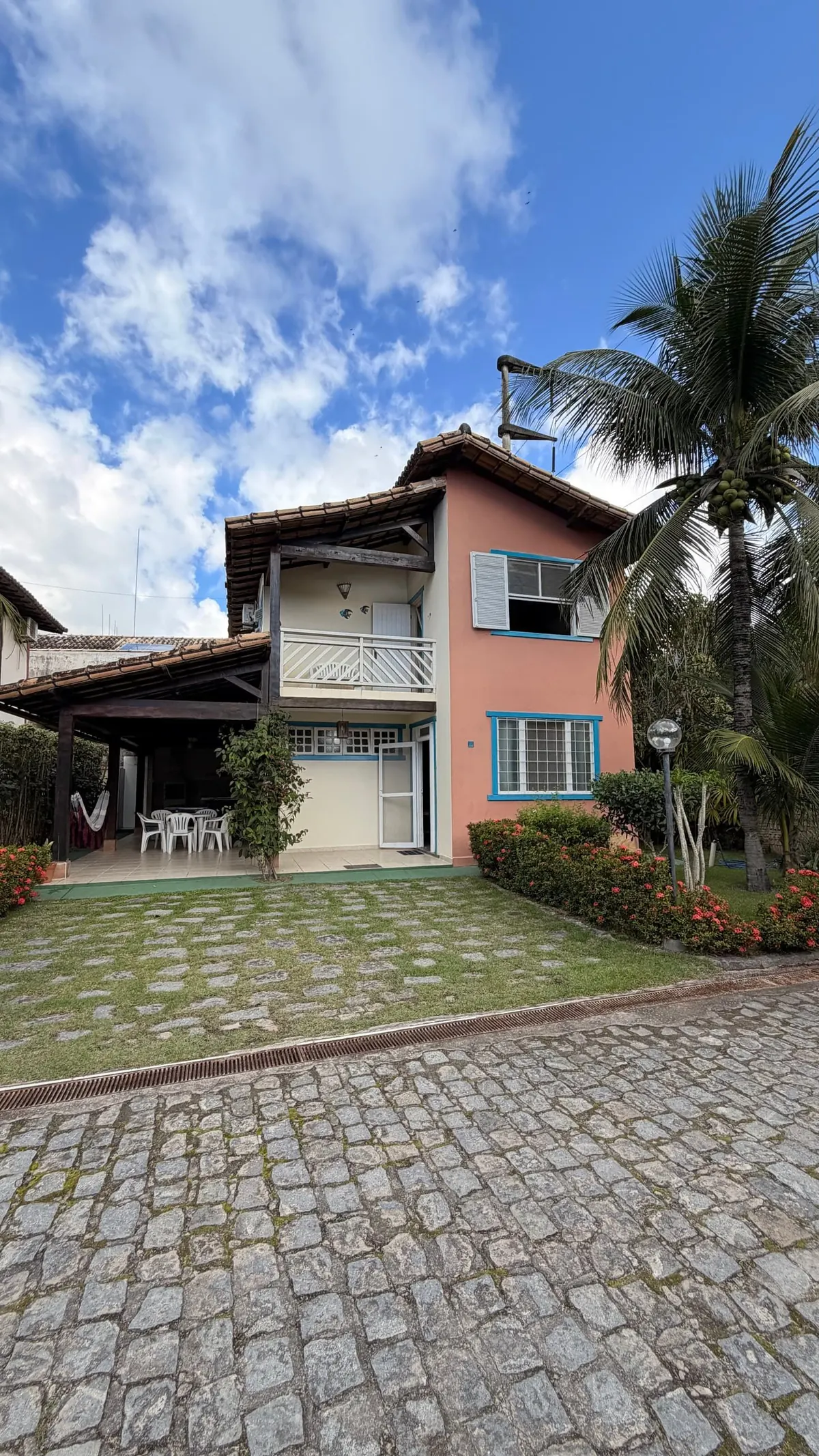 A casa, de dois andares, com varanda e gramado